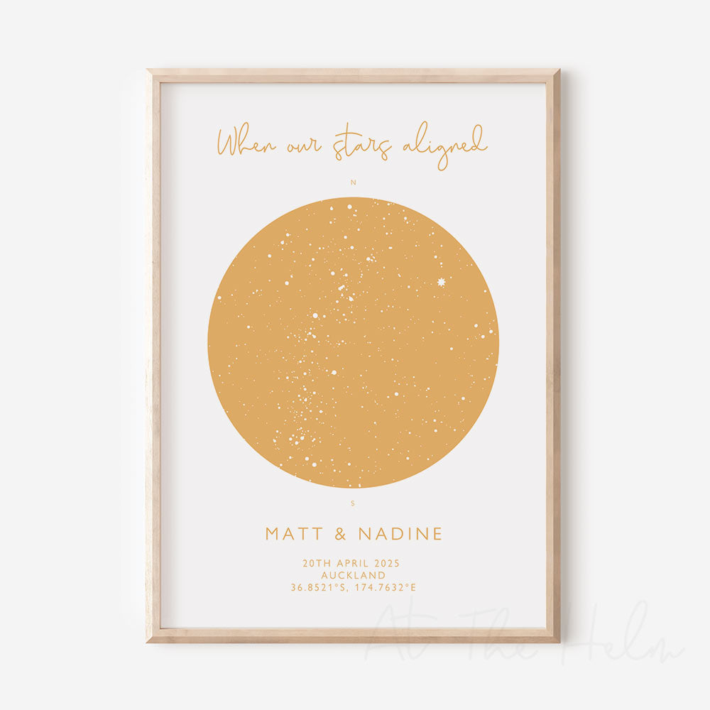 A framed custom star map print with the title 'When our Stars Aligned' and personalised text for 'Matt & Nadine, 20th April 2025, Auckland, 36.8521 174.7632' on the bottom, depicting a map of the stars on white photographic paper with yellow text and accents.