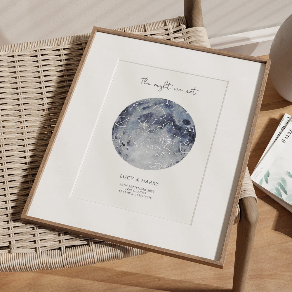 Framed blue watercolour star map print with text personalization.
Headline text reads " The Night We Met". Secondary text at the bottom reads " Lucy & Harry" and then a personalised special date, location and map coordinates.