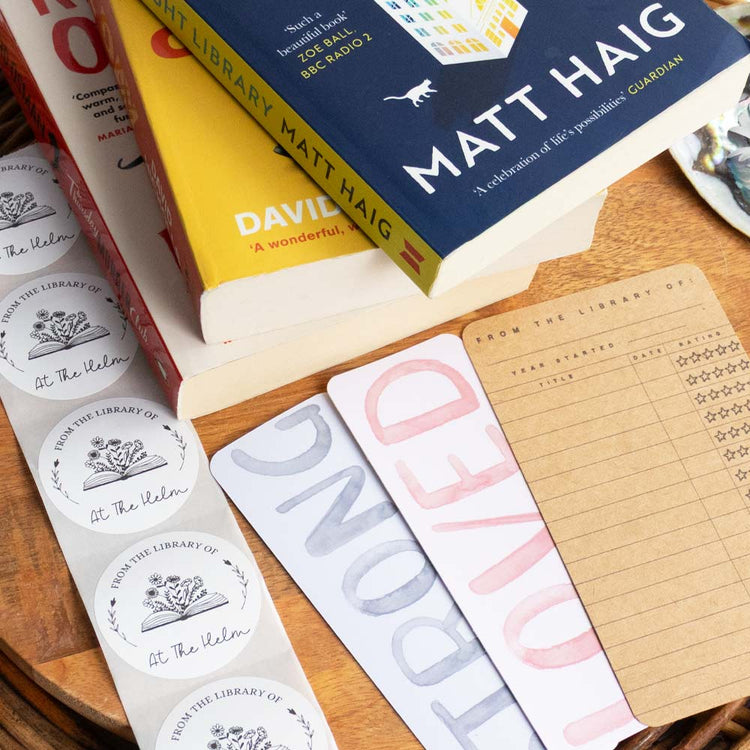 An image if a stack of pre-loved books, some white personalised book stickers and a selection of bookmarks