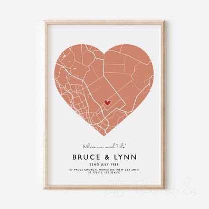 Framed orange and white heart-shaped map print with text personalization.

A red heart marks a specific location. 
Small cursive headline text reads " Where we said "i do"". Secondary capitalized text (slightly larger) below that reads " Bruce & Lynn"  and then a personalised special date, location and map coordinates. 