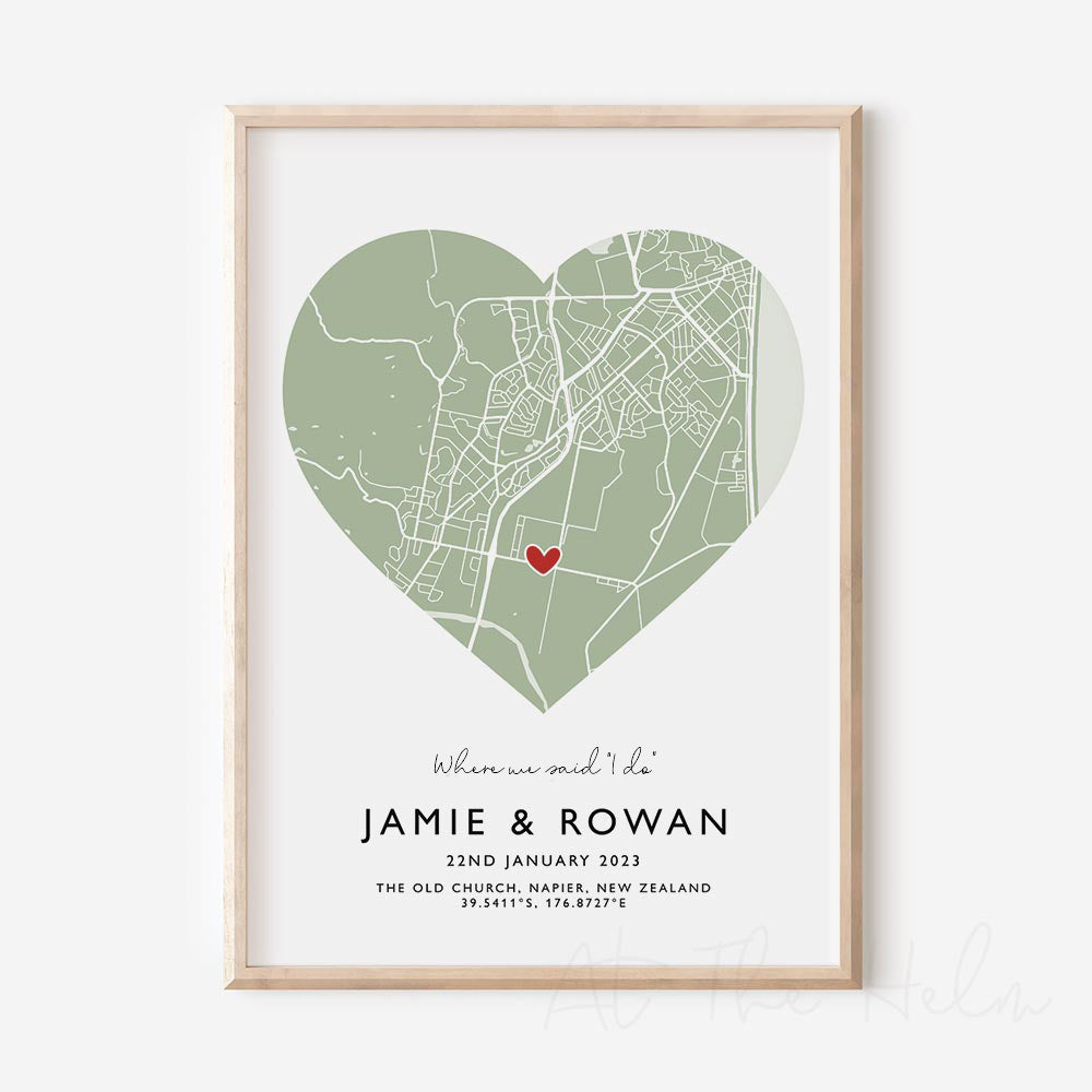 Framed sage green and white heart-shaped map print with text personalization.

A red heart marks a specific location. 
Small cursive headline text reads " Where we said "i do"". Secondary capitalized text (slightly larger) below that reads " JAMIE & ROWAN"  and then a personalised special date, location and map coordinates. 